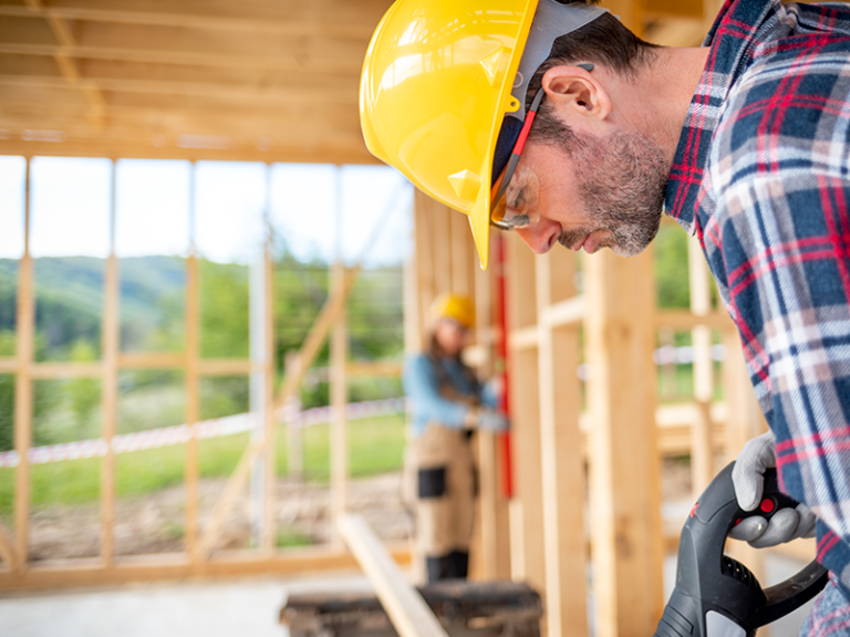 Two construction workers building a house